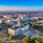 Fraud Alarm Blasts LA — Funding Cut State capitol building with dome in a cityscape at sunrise