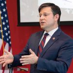 Profanity-Filled Hearing Rekindles COVID Debate Man in suit speaking at podium with US flag in background