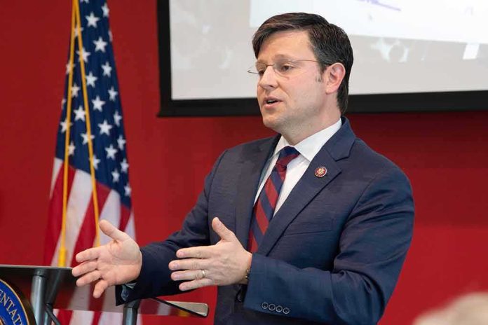 shutterstock_1381036358 Man in suit speaking at podium with US flag in background