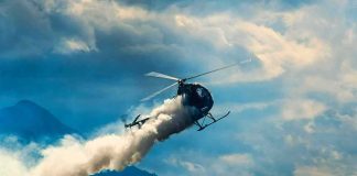 Helicopter releasing smoke over mountains