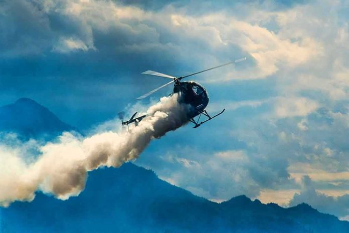 shutterstock_1429549637 Helicopter releasing smoke over mountains