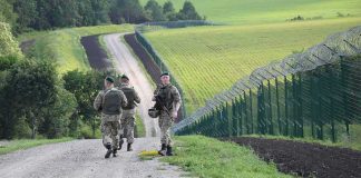 Soldiers patrolling along a rural border fence