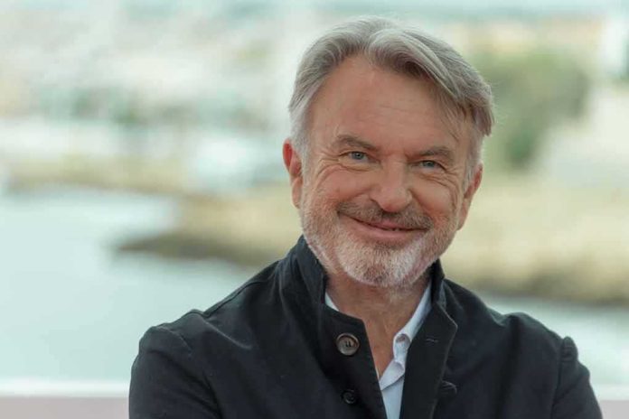 shutterstock_1560950744 Sam Neill smiling in a dark jacket outdoors