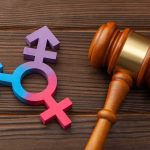 Wooden gavel beside multicolored transgender symbol