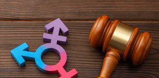 Wooden gavel beside multicolored transgender symbol