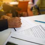 Worker hand filling out forms on a desk