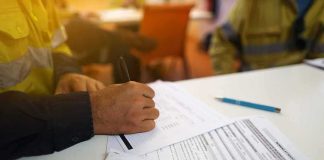 Worker hand filling out forms on a desk