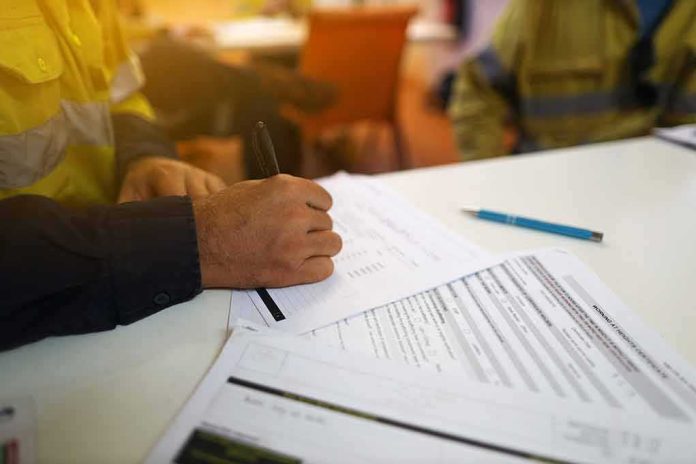 shutterstock_1625512909 Worker hand filling out forms on a desk