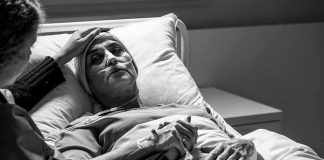 These COVID Hospital Stories Are Back in Washington Patient in hospital bed with nasal oxygen held by visitor