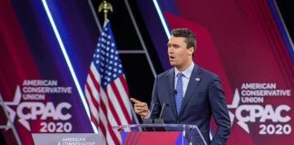 One Offensive Sign Puts City In Bind Speaker in suit at CPAC podium on stage