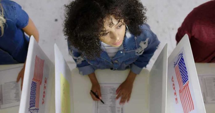 Woman filling out ballot at a voting booth