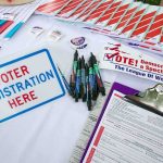 Court Move Could Nuke Mail Registration Voter registration table with forms, pens, and informational materials