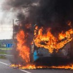 burning bus on highway with heavy black smoke