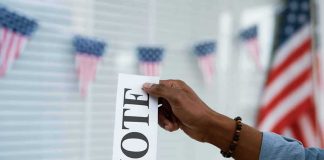 Hand placing a ballot into a wooden ballot box