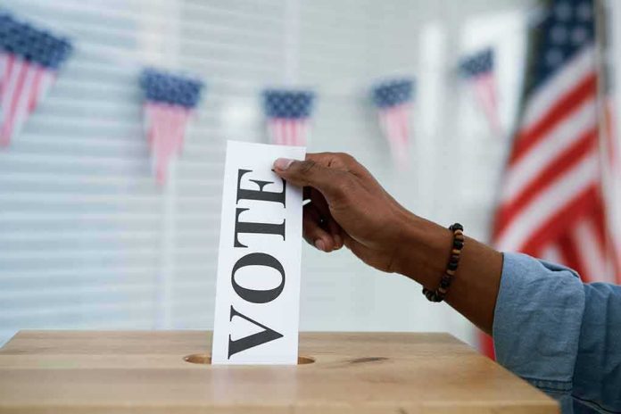 Hand placing a ballot into a wooden ballot box