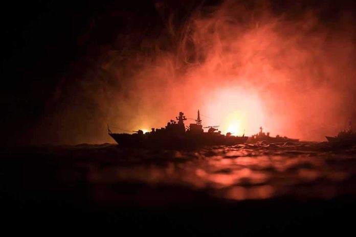 Warship silhouette at sea against fiery glow