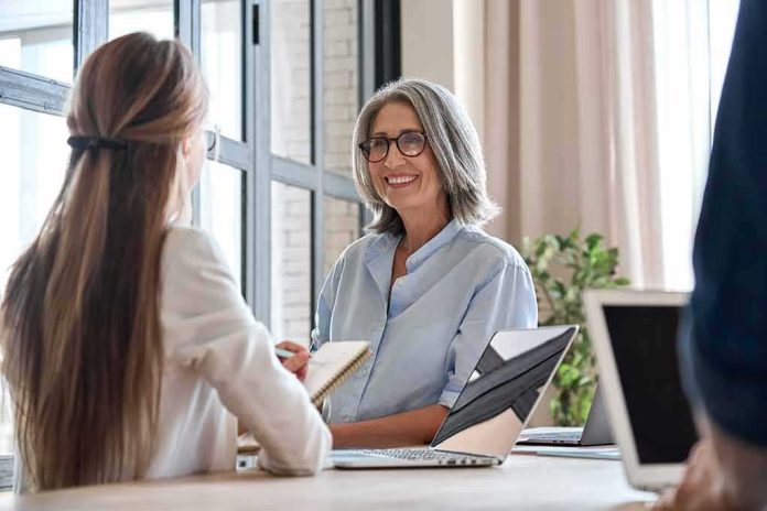 shutterstock_1954711978-1 Smiling woman with gray hair talking in a modern office