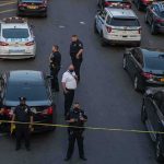 Gunman Vanishes After Park Ambush Police officers secure a street with patrol cars and yellow tape