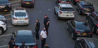 Gunman Vanishes After Park Ambush Police officers secure a street with patrol cars and yellow tape