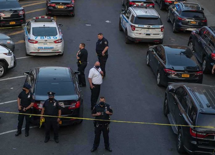 shutterstock_1976471639 Police officers secure a street with patrol cars and yellow tape