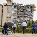 Tsunami Sirens Wail After 7.1 Partially collapsed beachfront apartment building with onlookers