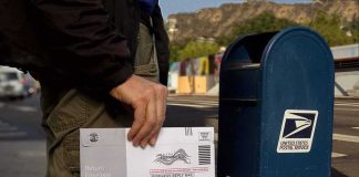 Ballot Tracking System Suddenly Frozen Person mailing a ballot envelope at a blue USPS street mailbox