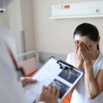 Prosecutors Agree: Mother Was Out of Reality Woman covering her face while doctor holds a clipboard in a hospital room