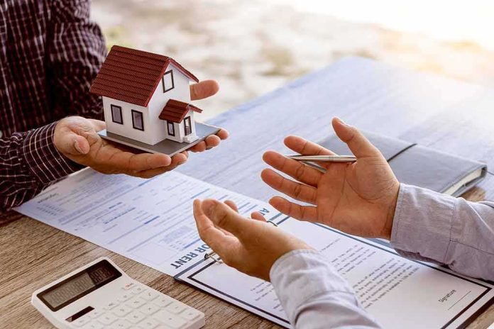Hands discussing real estate with a small house model and documents