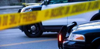 Police cars behind yellow caution tape at a street scene
