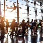 Standoff on Plane Ends In Shocking Detour Passengers queue inside an airport terminal at sunset