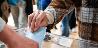 Hand inserting ballot into transparent box