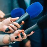 Strait Reopens, Nukes Still Humming Reporters holding colorful microphones