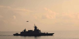 Warship cruising at sea during sunset