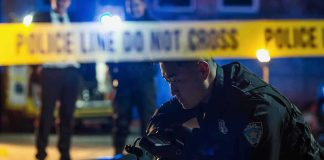 Pipe Call Morphs Into Deadly Blade Clash Police officer examines evidence at night behind caution tape