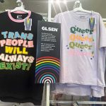Pride-themed T-shirts on store display with colorful slogans and rainbow sign
