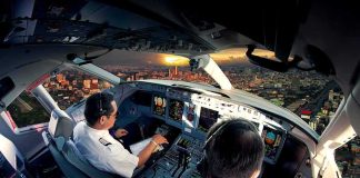 Pilots in an airplane cockpit during city approach at sunset