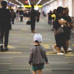child walking through a busy airport corridor