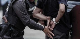 Police officer handcuffing a person against a vehicle