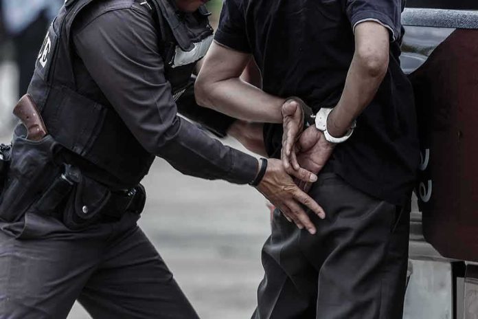 Police officer handcuffing a person against a vehicle