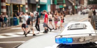 Tesla Crash Sparks Frat Liability Fight police car roof light bar with blue lights near a busy crosswalk