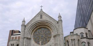Stone church facade with large rose window and cross