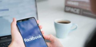 Person holding smartphone with Facebook app open