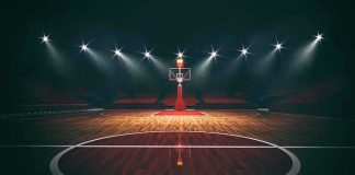 College Hoops Stunned: Dale Brown Dead Basketball hoop on an empty indoor court under bright arena lights