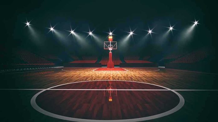 Basketball hoop on an empty indoor court under bright arena lights