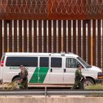 Border patrol van parked by tall metal fence