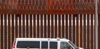 Border patrol van parked by tall metal fence