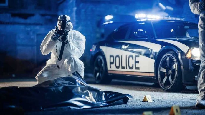 shutterstock_2230642401-1 forensic investigator photographing crime scene near police car