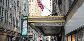 Needle Jab In Midtown – Bias Fears Explode Andreas Hestler and pedestrians outside The Roosevelt Hotel entrance on a city sidewalk