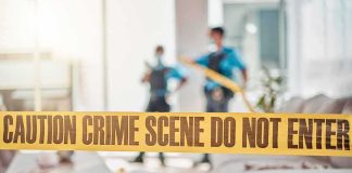 Police Investigate Assault Behind Locked Bathroom Door crime scene tape in a living room with two officers in background