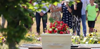 White coffin with red flowers at outdoor burial